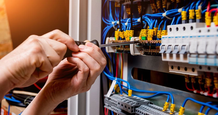 The man is repairing the switchboard voltage with automatic switches.